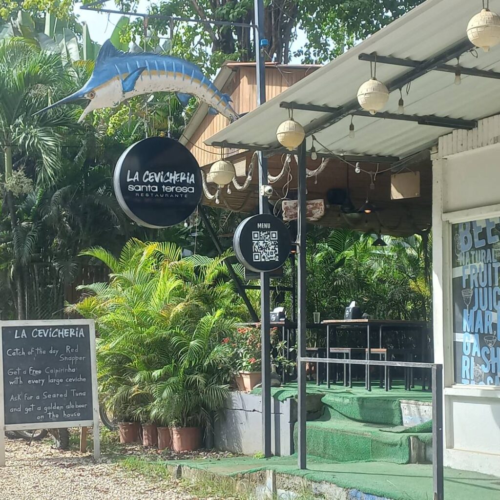 Outdoor café entrance with greenery and signage.