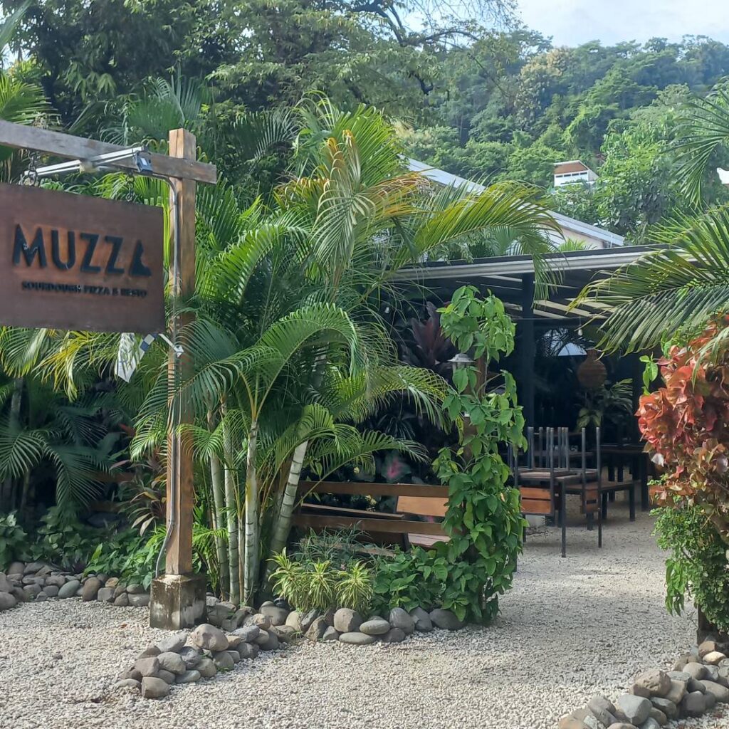 A cozy outdoor café surrounded by lush greenery and palm trees.