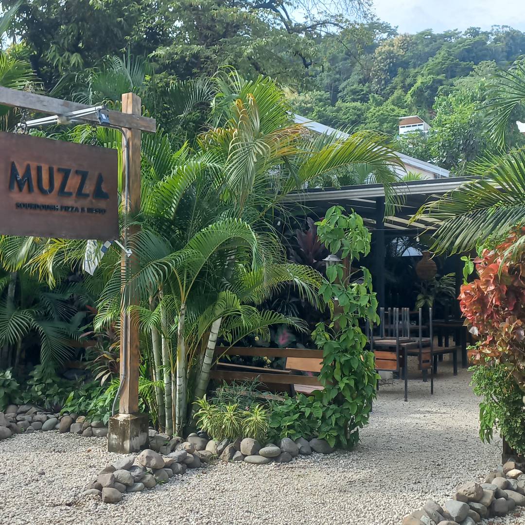 A cozy outdoor café surrounded by lush greenery and palm trees.