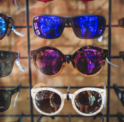 Colorful reflective sunglasses displayed on a rack.