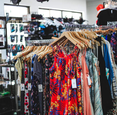 Colorful dresses hanging on wooden hangers in a clothing store.