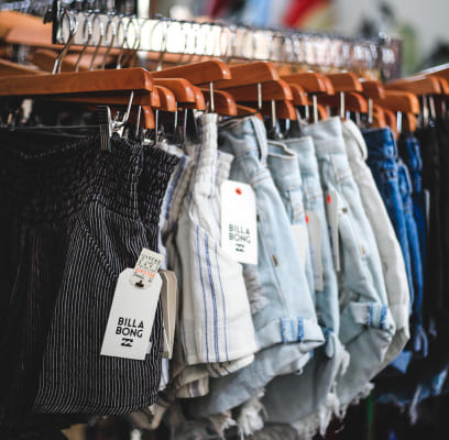 A rack of denim shorts in various shades hanging on wooden hangers.