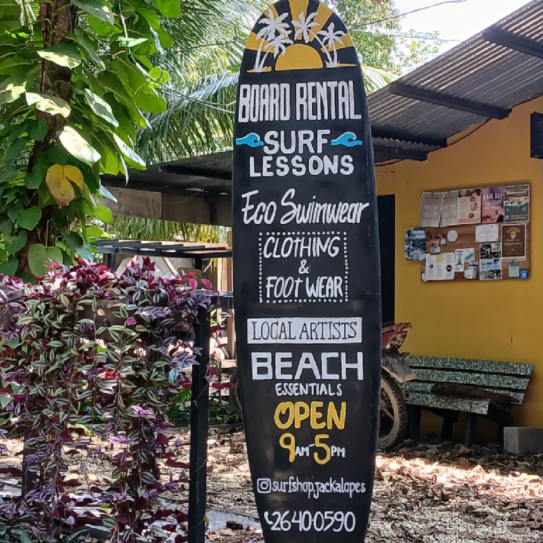 A colorful surf shop sign offering lessons and beach rentals.