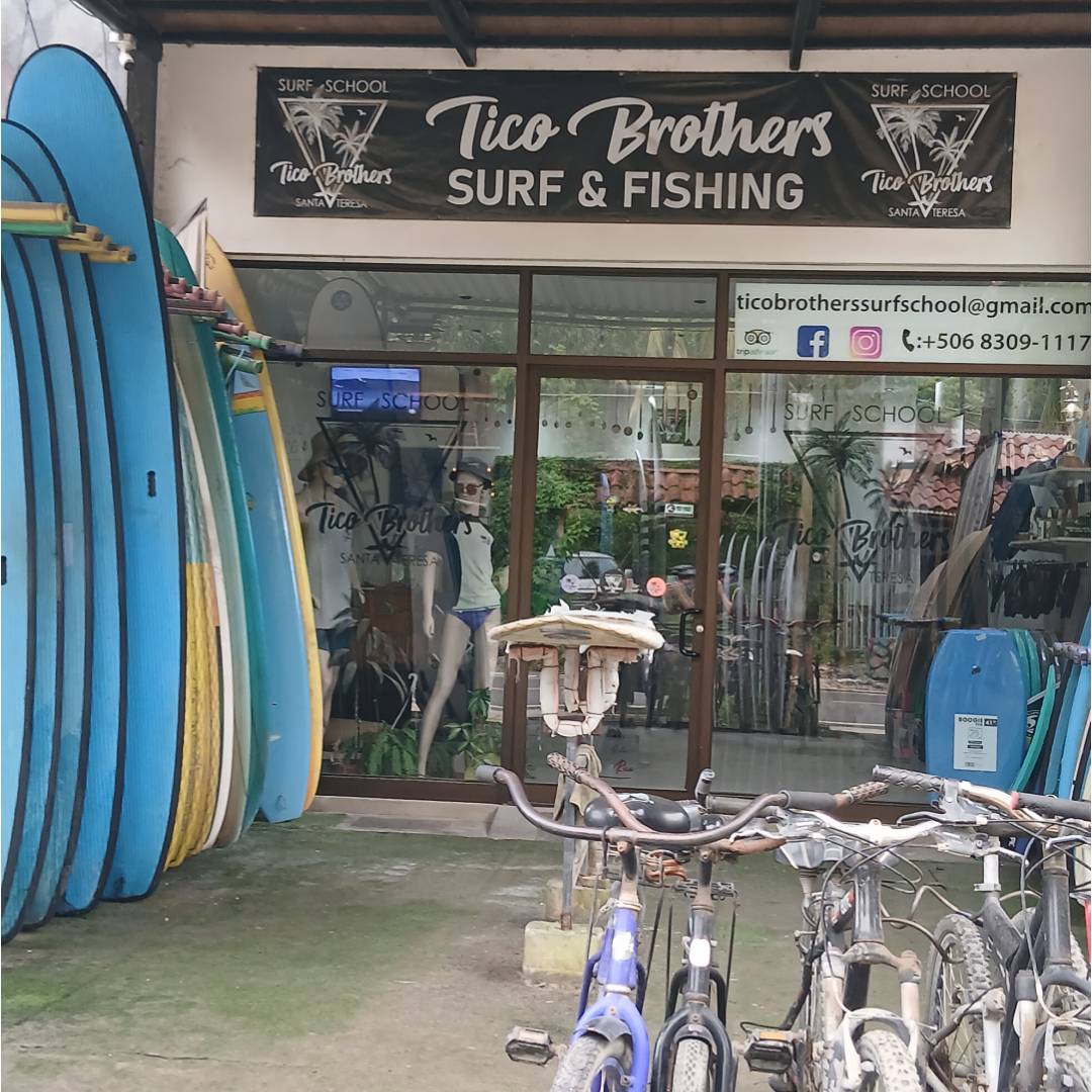 Entrance to Tico Brothers Surf & Fishing shop with surfboards and bicycles.