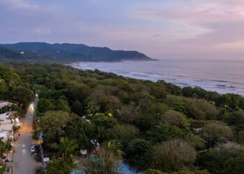 Aerial photo of Santa Teresa with jungle canopy, Pacific Ocean waves, and main street in Costa Rica