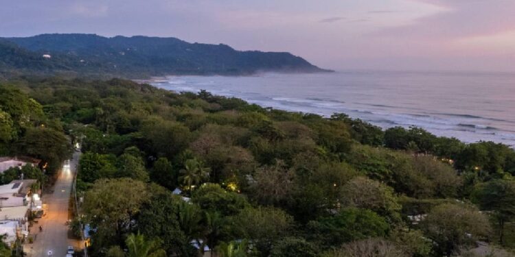 Aerial photo of Santa Teresa with jungle canopy, Pacific Ocean waves, and main street in Costa Rica