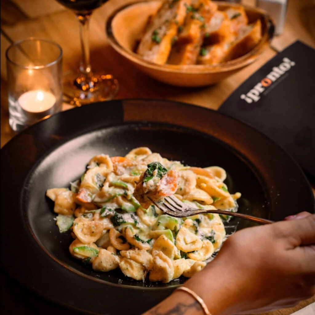 A rocky beach with palm trees under a clear blue sky.