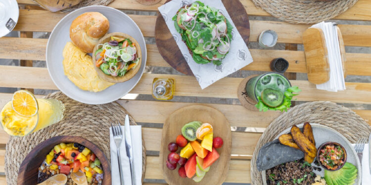 Blue Mist restaurant in Santa Teresa serving a beachfront breakfast with Pinto con Huevos, tropical fruit bowl, fresh breads, and a superfood drink overlooking the Pacific Ocean