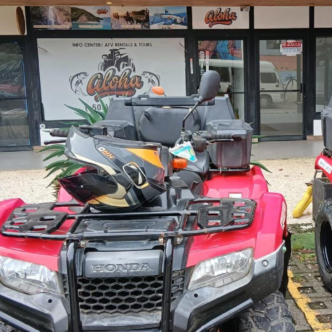 A red ATV parked outside a building with a man inside.
