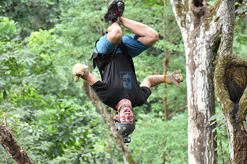 Man ziplining upside down through tropical forest in Costa Rica