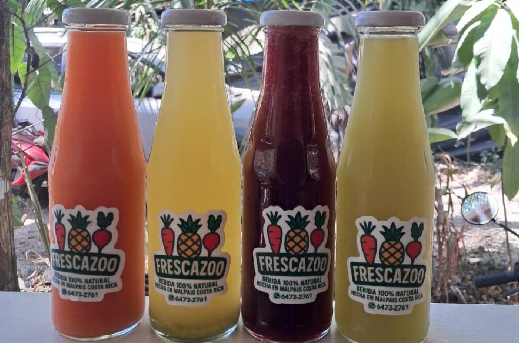 Four glass bottles of Frescazoo fresh juice in Santa Teresa Costa Rica featuring carrot, starfruit, beet carrot ginger, and pineapple basil blends made with local ingredients.