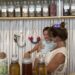 Yuli, clinical herbalist and owner of Marpe Jungle Apothecary, standing with her child at her shop counter surrounded by jars of dried herbs and teas in Santa Teresa Costa Rica