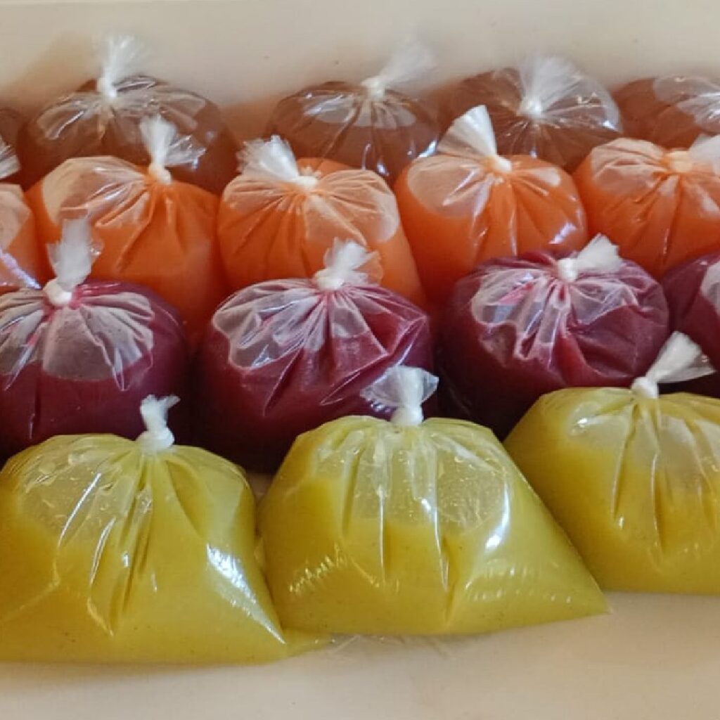 Early Frescazoo juices sold in plastic baggies in Costa Rica featuring aguazapo, carrot apple, beet carrot ginger, and pineapple hierba buena street-style drinks.