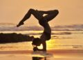 Nancy practicing yoga on the beach at sunset with the Pacific Ocean behind her in Santa Teresa