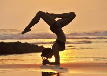 Nancy practicing yoga on the beach at sunset with the Pacific Ocean behind her in Santa Teresa