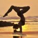 Nancy practicing yoga on the beach at sunset with the Pacific Ocean behind her in Santa Teresa