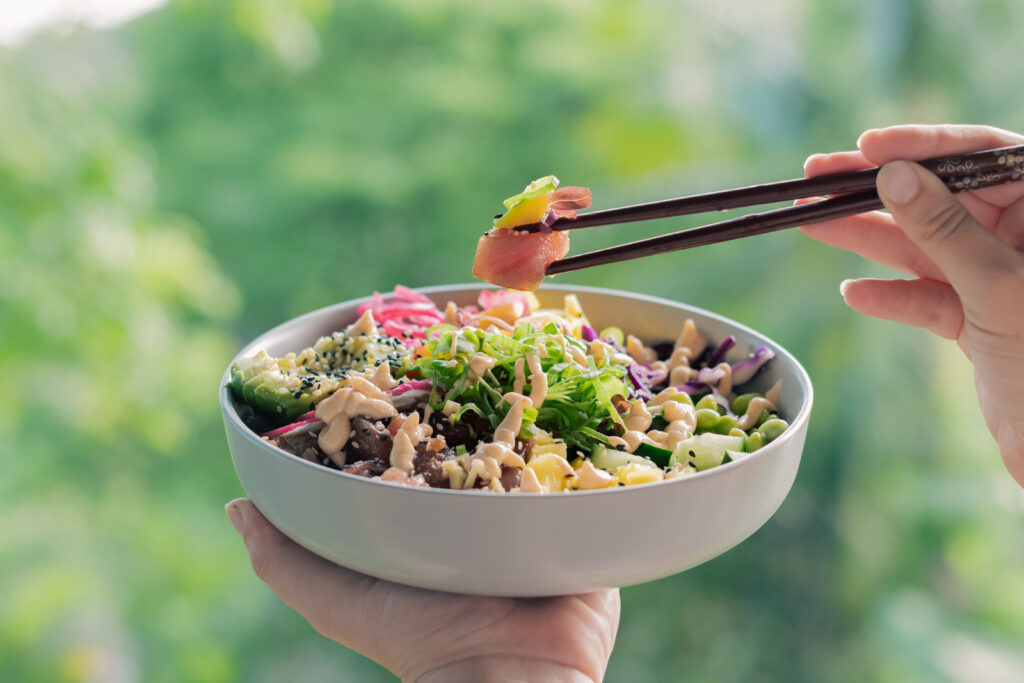 Fresh tuna poke bowl with mango avocado and chopsticks lifting raw tuna Santa Teresa Costa Rica