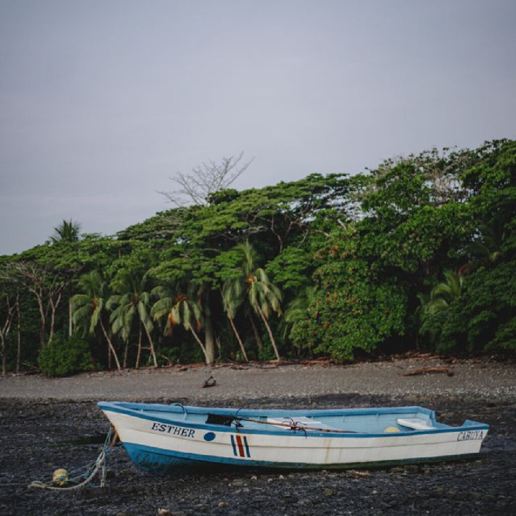 Traditional fishing boat pulled onto shore in Malpais Costa Rica with jungle backdrop