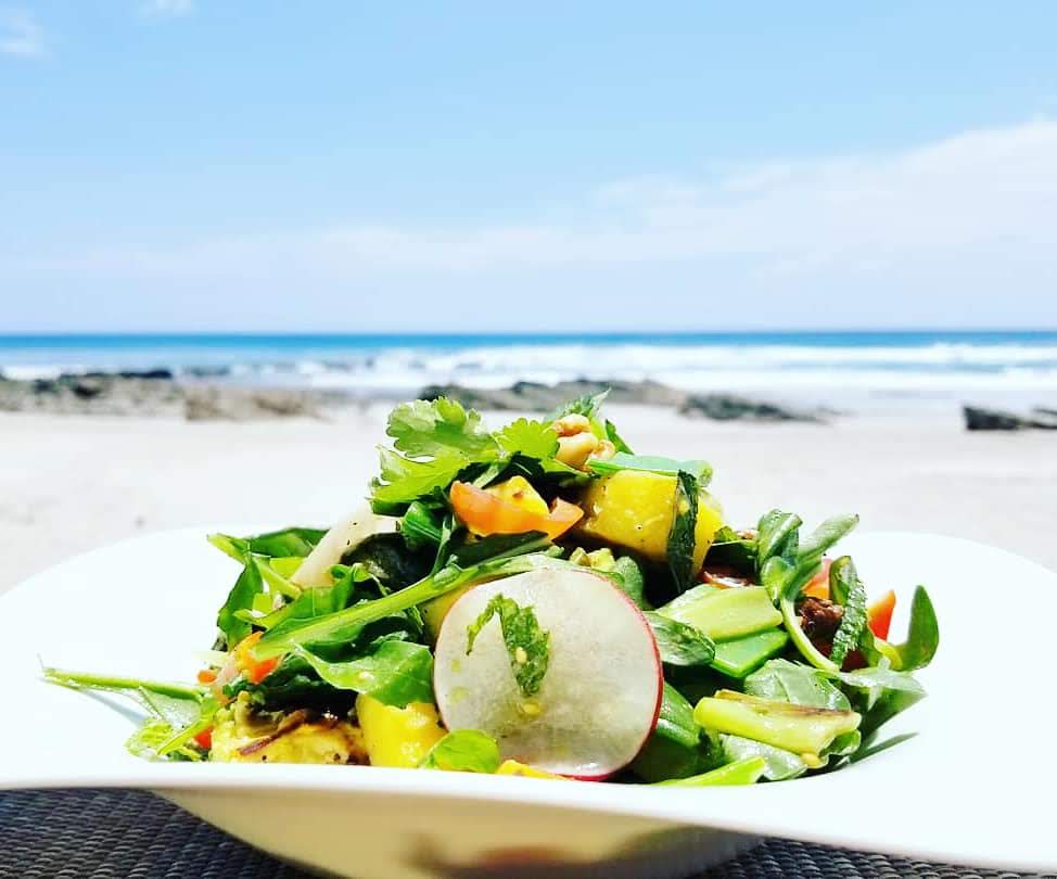 Fresh local salad with mango radish greens and ocean background Costa Rica