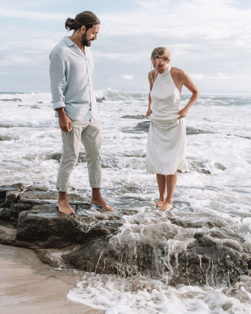 Couple standing barefoot on rock surrounded by ocean water Costa Rica