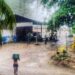 Woman walking through heavy rain in Mal País, Costa Rica, using a bucket for shelter during a tropical rainy season storm near Mar Azul.
