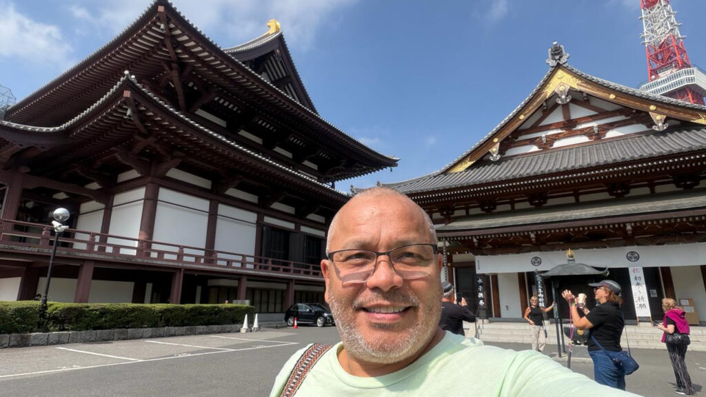 Alan standing in Tokyo, Japan, with traditional Japanese architecture in the background during his world travels.